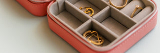 Pink jewelry box with gold rings and earrings organized in compartments