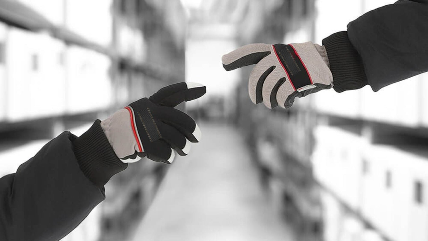 Two people wearing protective work gloves reaching toward each other in a warehouse aisle