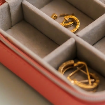 Pink jewelry box with gold rings and earrings organized in compartments