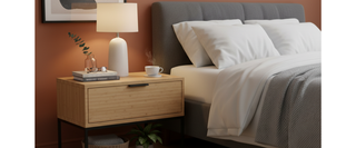 Modern bedroom with grey upholstered bed, bamboo nightstand, lamp, and minimal decor