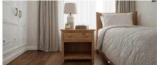 Modern bedroom with wooden nightstand, table lamp, books, and neutral bedding