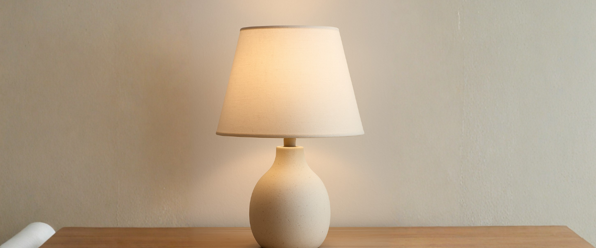 Modern beige table lamp with fabric shade on wooden surface, minimalist home decor