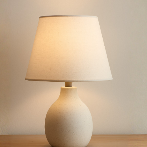 Modern beige table lamp with fabric shade on wooden surface, minimalist home decor