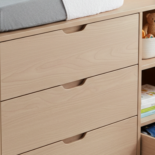 Light wood nursery dresser with changing pad, storage shelves, baby clothes, and books