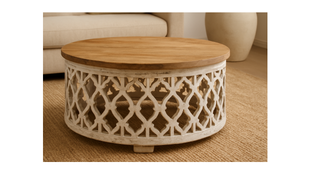 Round wooden coffee table with carved lattice base in a cozy living room setting