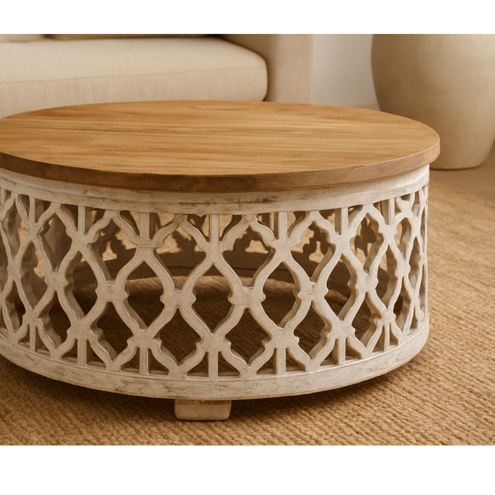 Round wooden coffee table with carved lattice base in a cozy living room setting