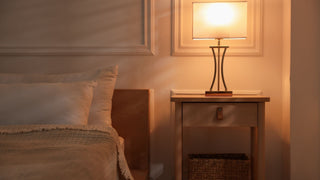 Cozy bedroom with bedside table, modern lamp, and soft bedding in warm lighting