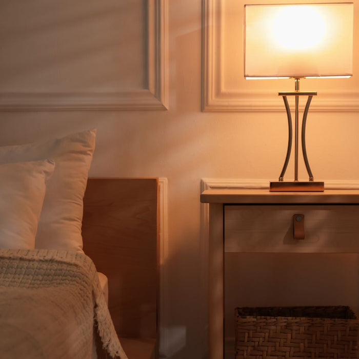 Cozy bedroom with bedside table, modern lamp, and soft bedding in warm lighting