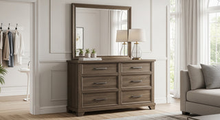 Modern wood dresser with six drawers and large mirror in bright bedroom, featuring table lamp and decorative plants.