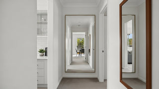 Modern hallway with large wall mirrors, neutral decor, and a glimpse of a dining area