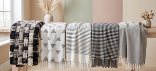 Range of black and white throws in soft textures on a pastel backdrop.