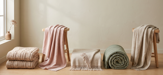 Range of couch throws in soft textures on a pastel backdrop.