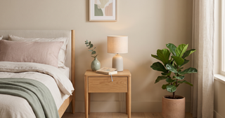 Small bedside table with a lamp beside a bed in a calm, compact bedroom.
