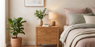 Timber bedside table with a lamp beside a bed in a calm, elegant bedroom.