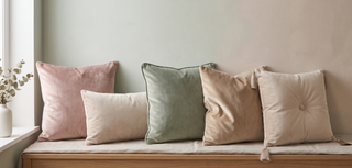 Range of velvet cushions with a soft sheen on a pastel backdrop.