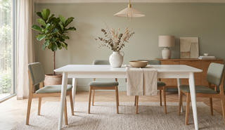 White dining table styled with a vase in a calm, elegant dining room.