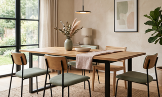 Wooden dining table with metal legs styled with a vase in a calm, elegant dining room.