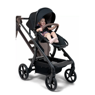 Smiling baby sitting in a modern black stroller with canopy and large wheels