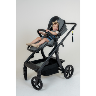 Smiling baby sitting in a modern grey stroller with large wheels indoors