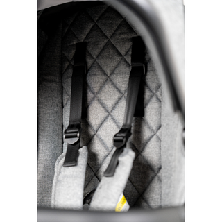 Close-up of grey quilted stroller seat with adjustable black safety harness straps