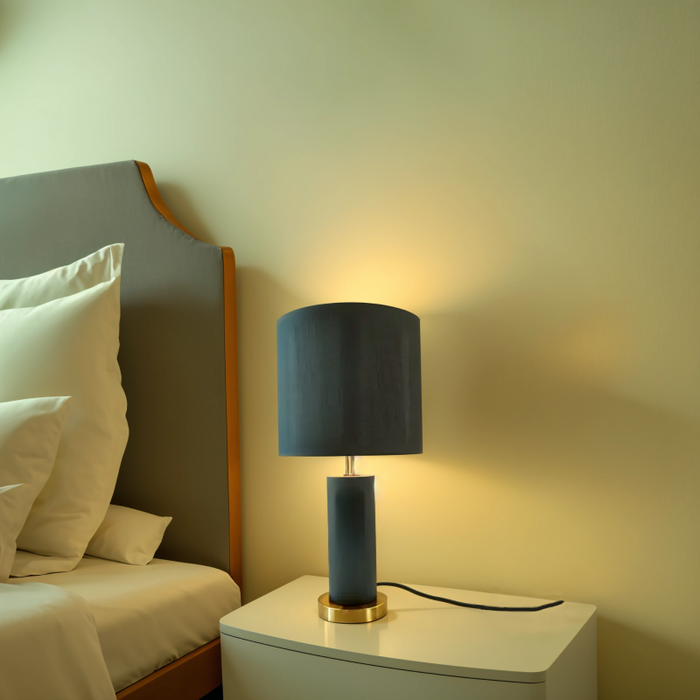 Modern bedside lamp black metal gold placed on nightstand beside white bedding.