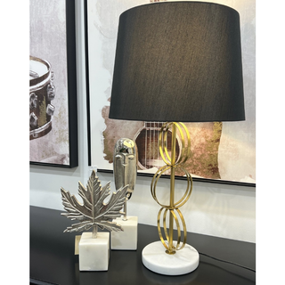 Decorative table lamp with a black shade on a console table with decorative items.
