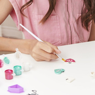 Hand painting a heart-shaped pendant with Cool Maker Clay Craft Kit