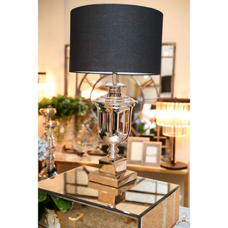 Paddington Silver Lamp with black shade displayed on mirrored console in elegant interior setting.