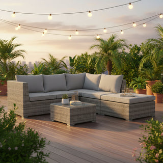 An outdoor sectional sofa set with a chaise lounge and a matching rectangular coffee table, featuring gray cushions and woven gray-brown wicker frames, shown in a beautiful outdoor setting area