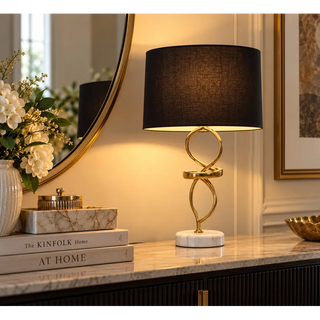 Abstract gold and marble table lamp on black fluted sideboard beside round brass mirror