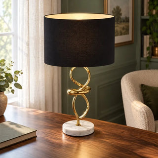 Abstract gold and marble table lamp on walnut desk in green panelled study