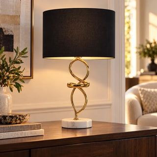 Abstract gold and marble table lamp on walnut sideboard against panelled cream wall
