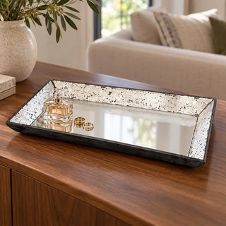 Antique rectangular glass tray on walnut sideboard with perfume bottle and gold rings