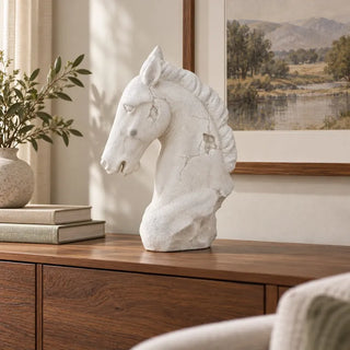 Antiqued white horse head bust on walnut sideboard beside landscape painting