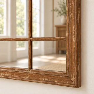 Arch wood trim panelled elongated mirror distressed brown frame bottom corner close up