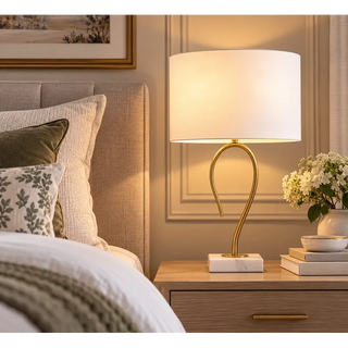 Art gallery front desk lamp lit on oak bedside table beside upholstered bedhead