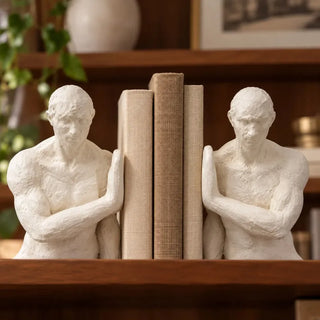 Athletic figure bookend set close up bracing linen books on wooden bookshelf