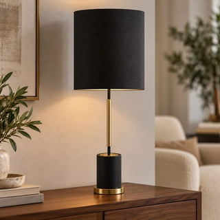 Bella tall table lamp lit on walnut sideboard beside cream boucle armchair