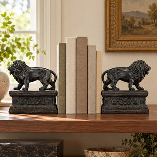  Black lion bookends pair with linen books on walnut shelf below gilt framed painting