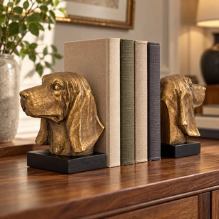 Bloodhound head bookend set with linen books on wooden sideboard beside ceramic vase