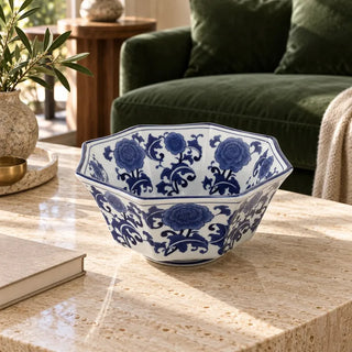 Blue and white centerpiece bowl on travertine coffee table beside green velvet sofa