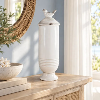 Ceramic jar with bird lid on cane sideboard below round woven mirror