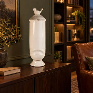 Ceramic jar with bird lid on dark wood sideboard beside brown leather armchair