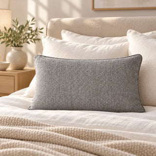Charcoal grey weave cushion on white bedding with cream headboard