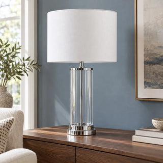 Chrome glass lamp on walnut sideboard against blue wall beside cream armchair