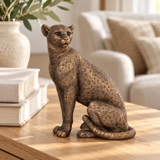 Copper panther statue on light oak table beside olive branch vase and cream sofa