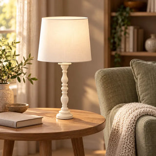 Country creamy table lamp on round oak side table beside sage green armchair