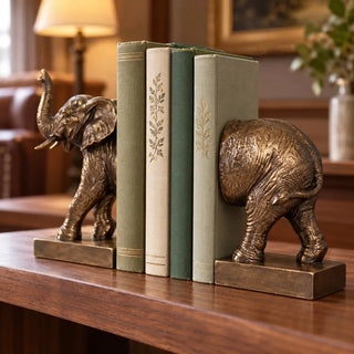 Elephant bookend set head and tail halves with sage green books on walnut shelf