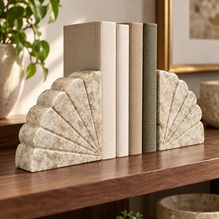 Fan shaped marble bookend set on walnut shelf beside potted plant and gold framed art