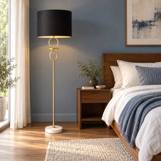 Gold and black metal floor lamp with marble base in blue bedroom beside walnut bedside table